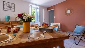 Un coin repas avec une table en bois, un vase de fleurs et un panier de pain.