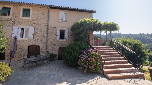 Un bâtiment en pierre avec un escalier menant à une zone abritée.