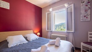 Une chambre à coucher avec un lit, une fenêtre donnant sur un paysage agréable, un radiateur et une chaise.