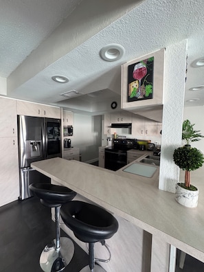 Eine moderne Küche mit Edelstahlgeräten, einer Marmorarbeitsplatte und einem Blumentopf.