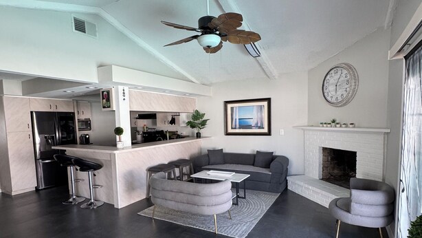 A modern living room with a sofa, a dining area, a kitchen, and a fireplace. - Sun, Pool & Beach: Largo Getaway (Largo)