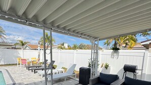 A covered patio area with outdoor furniture, a grill, and a pool. - Sun, Pool & Beach: Largo Getaway (Largo)