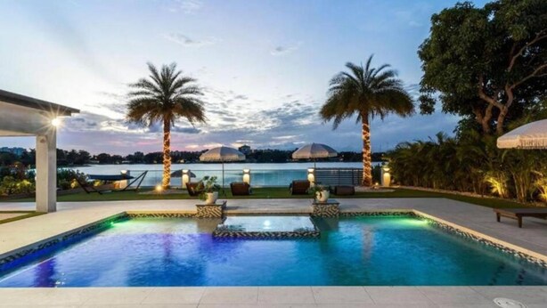 A swimming pool with a view of a dome-shaped building, palm trees, and a covered seating area.