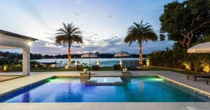 A swimming pool with a view of a dome-shaped building, palm trees, and a covered seating area. - Star Villa Opulent Waterfront Property (North Miami Beach)