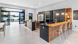 A modern kitchen with a central island, bar stools, and a view of the outdoors.