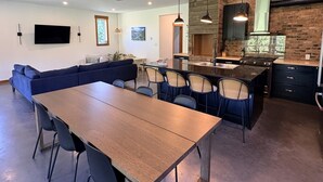 Une cuisine moderne avec un coin repas, des appareils électroménagers intégrés et une grande table en bois.