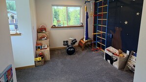 Une salle de jeux pour enfants avec une batterie, une échelle d’escalade et un mur décoré sur le thème des étoiles.