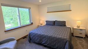 Une chambre à coucher avec un grand lit, deux tables de chevet, une fenêtre et une chaise.