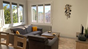 Een moderne woonkamer met een grijze bank, een houten salontafel en een radiator.