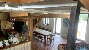 Un intérieur rustique avec une table à manger en bois, un baby-foot et un coin cuisine équipé d’une cuisinière et d’un évier.