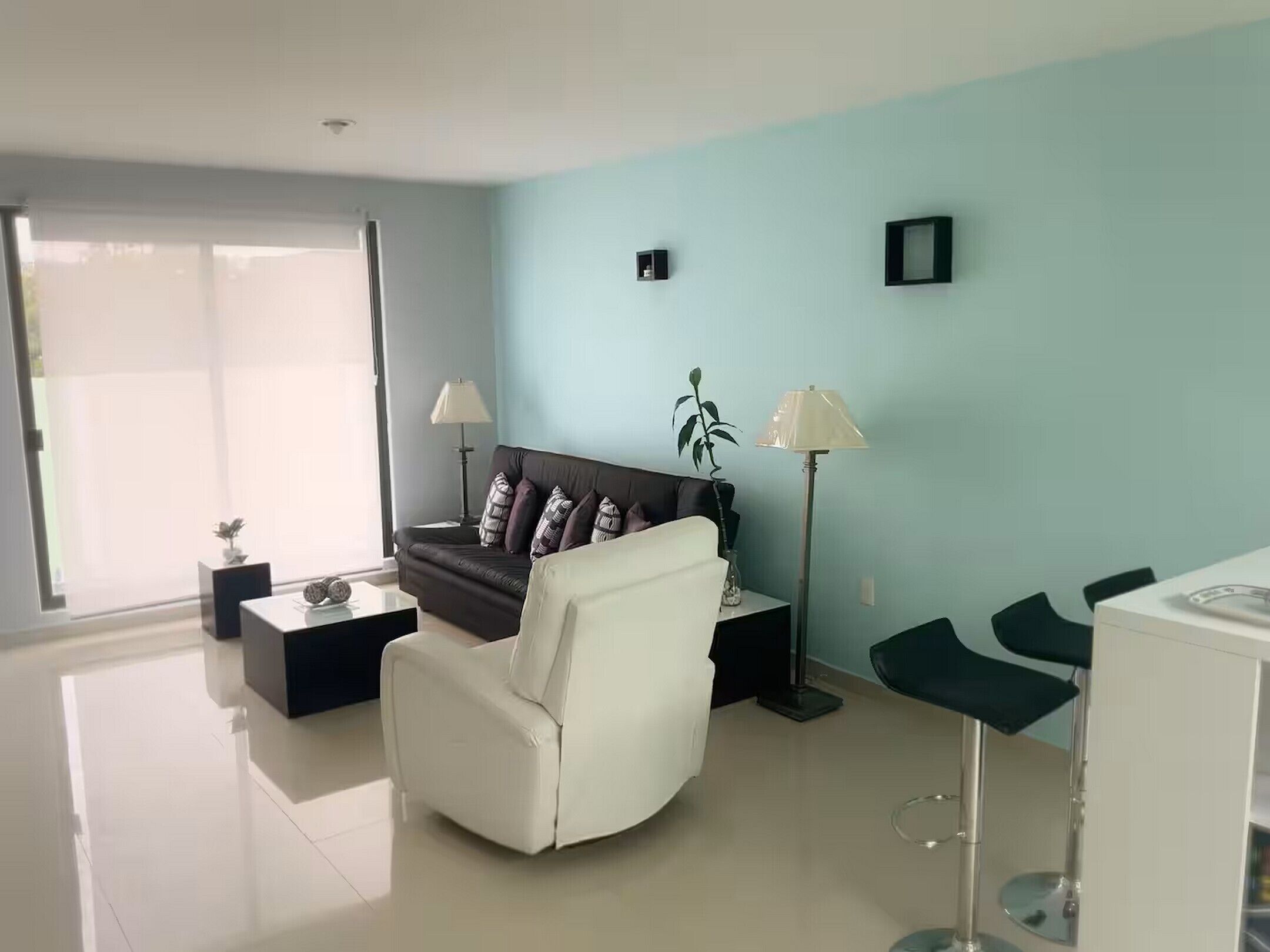 A modern living room with a sofa, a white armchair, a coffee table, a floor lamp, and a small table with a lamp.
