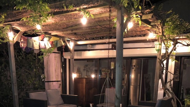 Une terrasse extérieure dotée d’un plancher en bois, d’un coin salon avec deux canapés, une petite table et une plante décorative dans un pot en mosaïque.