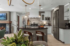Una cocina moderna con una isla central, electrodomésticos de acero inoxidable y una chimenea.
