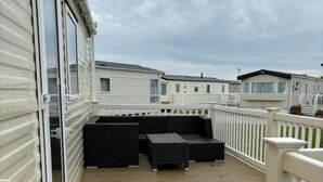 A deck with outdoor furniture, a white railing, and a view of other mobile homes. - cosy camber home from home caravan (Camber)