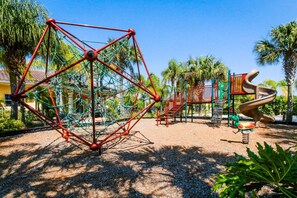 A playground with a climbing structure, slides, and swings. - Friendly Condo With Shared Pool and Hot Tub, High-speed Wifi, and Central AC (Kissimmee)