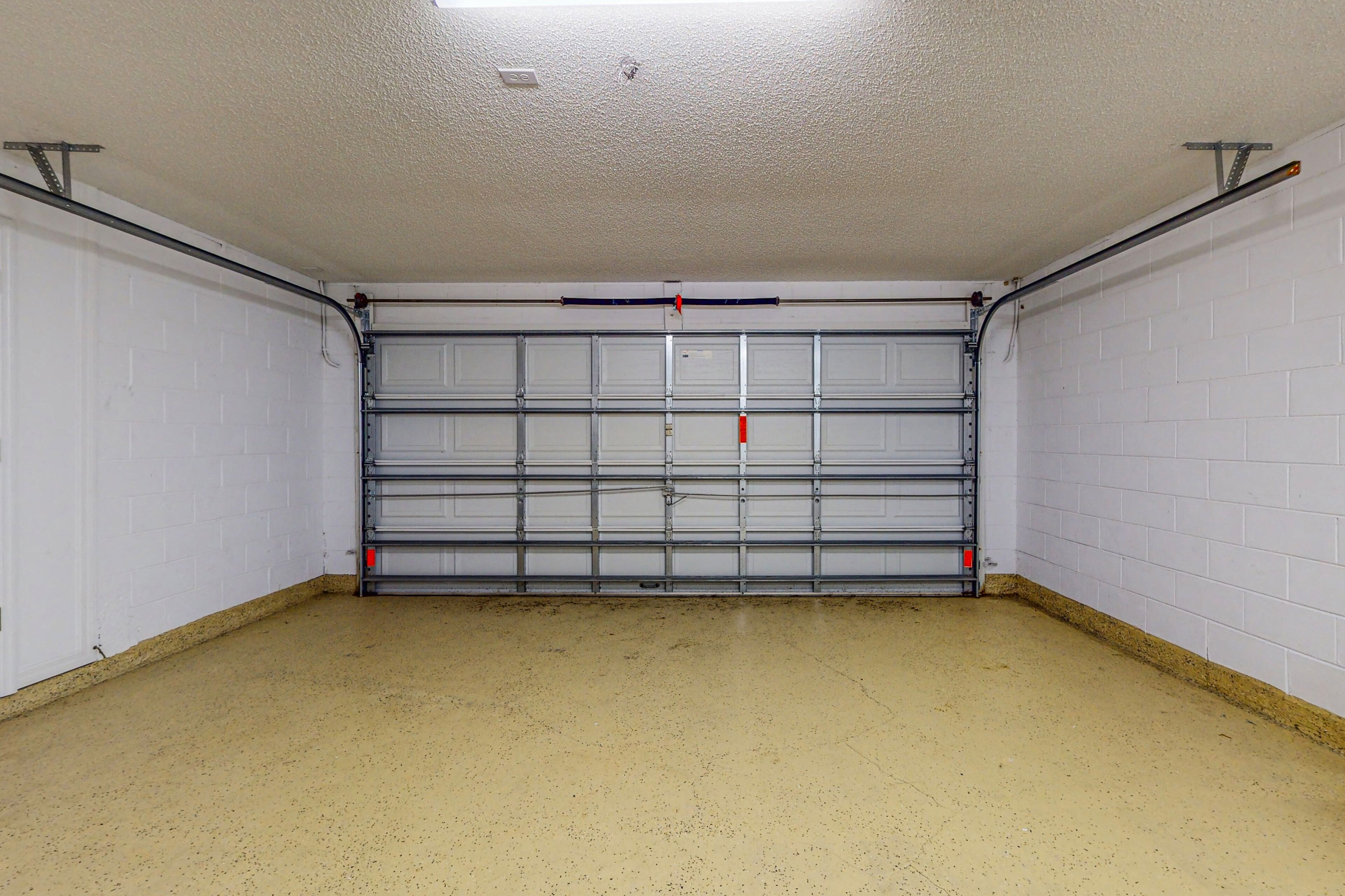 Un garage avec un sol en béton et des murs en briques blanches.