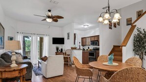 Ein geräumiger Wohnbereich mit Esstisch, Korbstühlen, Deckenventilator und einer Küche im Hintergrund.