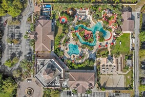 An aerial view of a resort with multiple swimming pools, a parking area, and surrounding greenery. - Townhouse Near Disney With Pool, Lazy River, Game Room, Gym, hot Tub, Volleyball (Davenport)