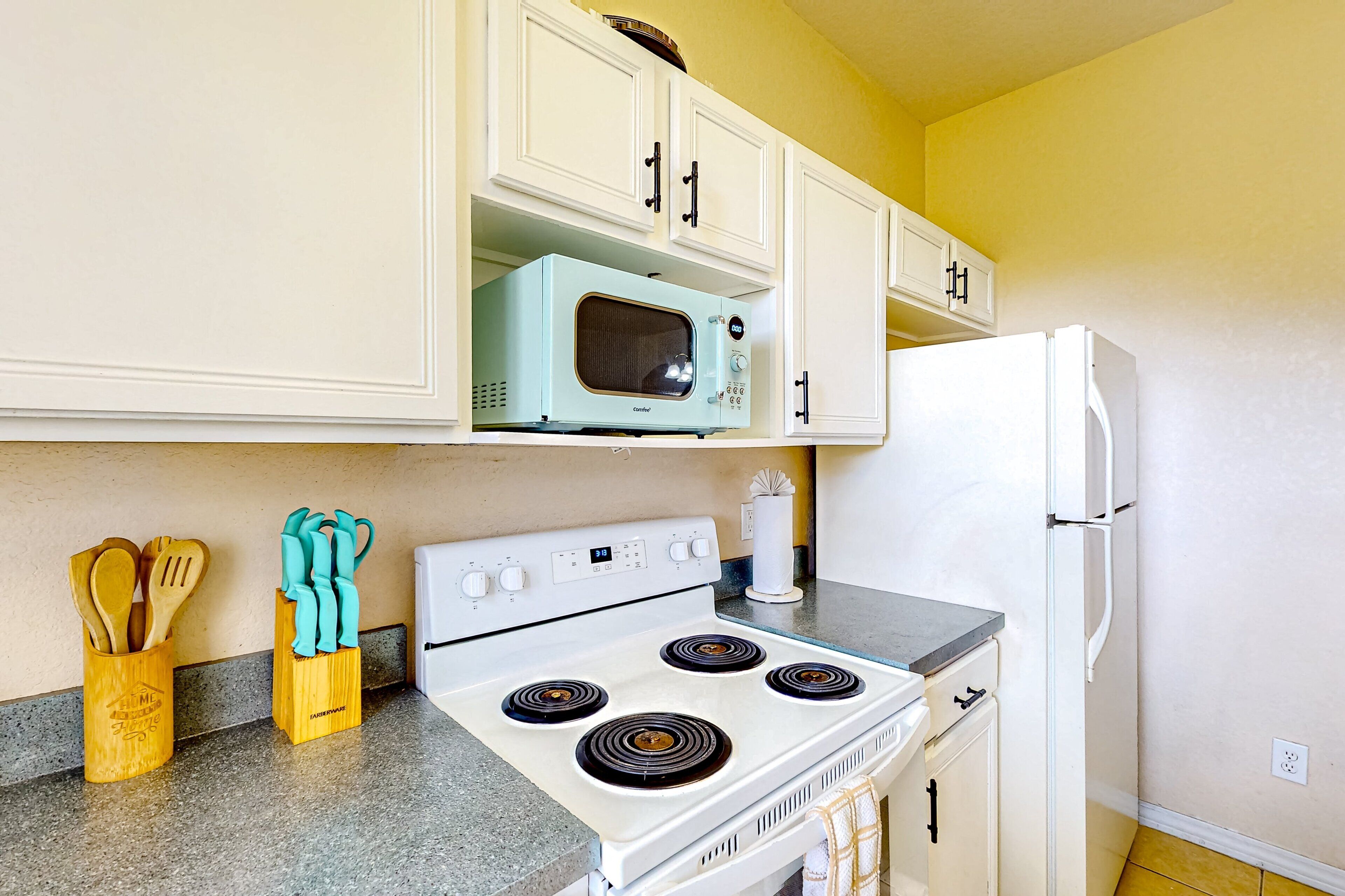 A kitchen with white cabinets, a white stove, a white refrigerator, and a microwave.