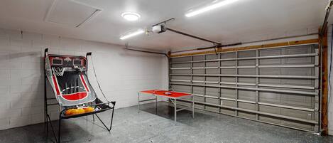 Una canasta de baloncesto, una mesa de ping pong y una puerta de garaje en un garaje.