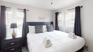 A neatly made bed with pillows, a bedside table with a lamp, and a ceiling fan. - Dog-friendly Home With Lake Views, Ping-pong, air Hockey, Streaming, W/d, & AC (Kissimmee)