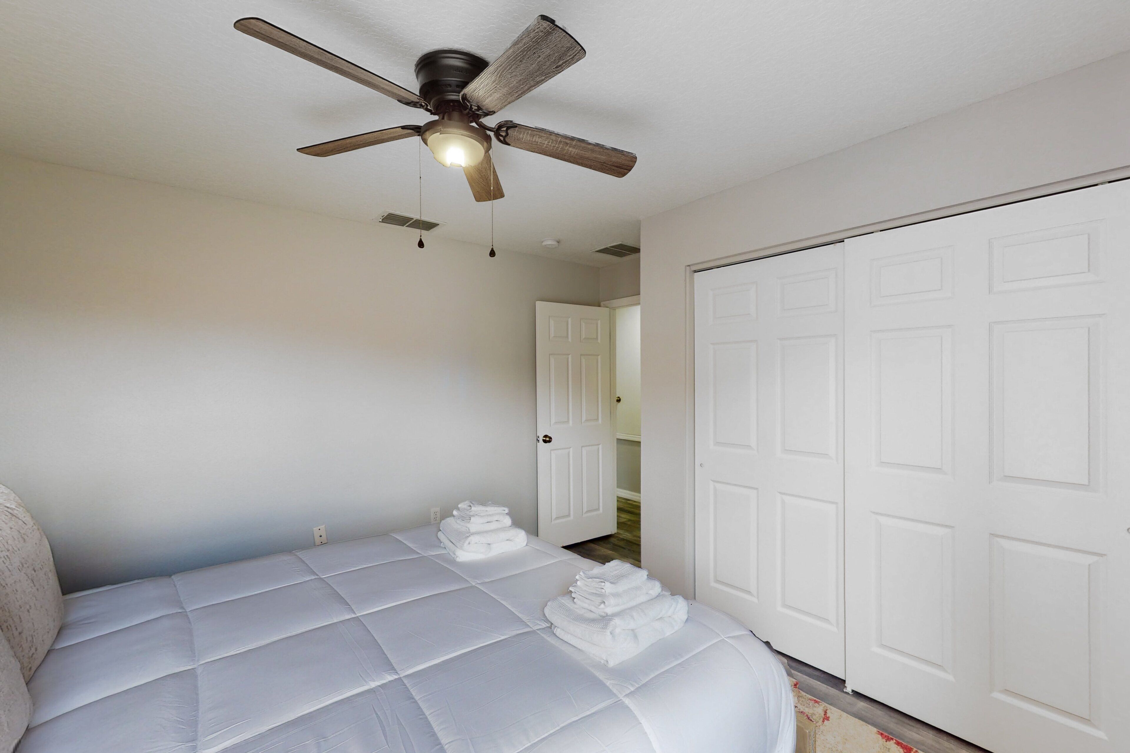 A bedroom with a bed, a ceiling fan, and a white door.