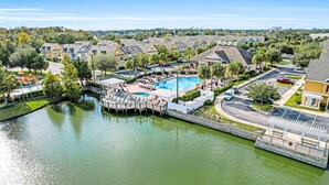 A residential area with a swimming pool, a dock, and a bridge over a canal. - Snowbird-friendly Condo Near Disney and Orlando With Outdoor Pool, Fast Wifi, W/D (Kissimmee)