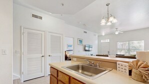 A kitchen with a large island, a double door, and a ceiling fan. - Snowbird-friendly Condo Near Disney and Orlando With Outdoor Pool, Fast Wifi, W/D (Kissimmee)