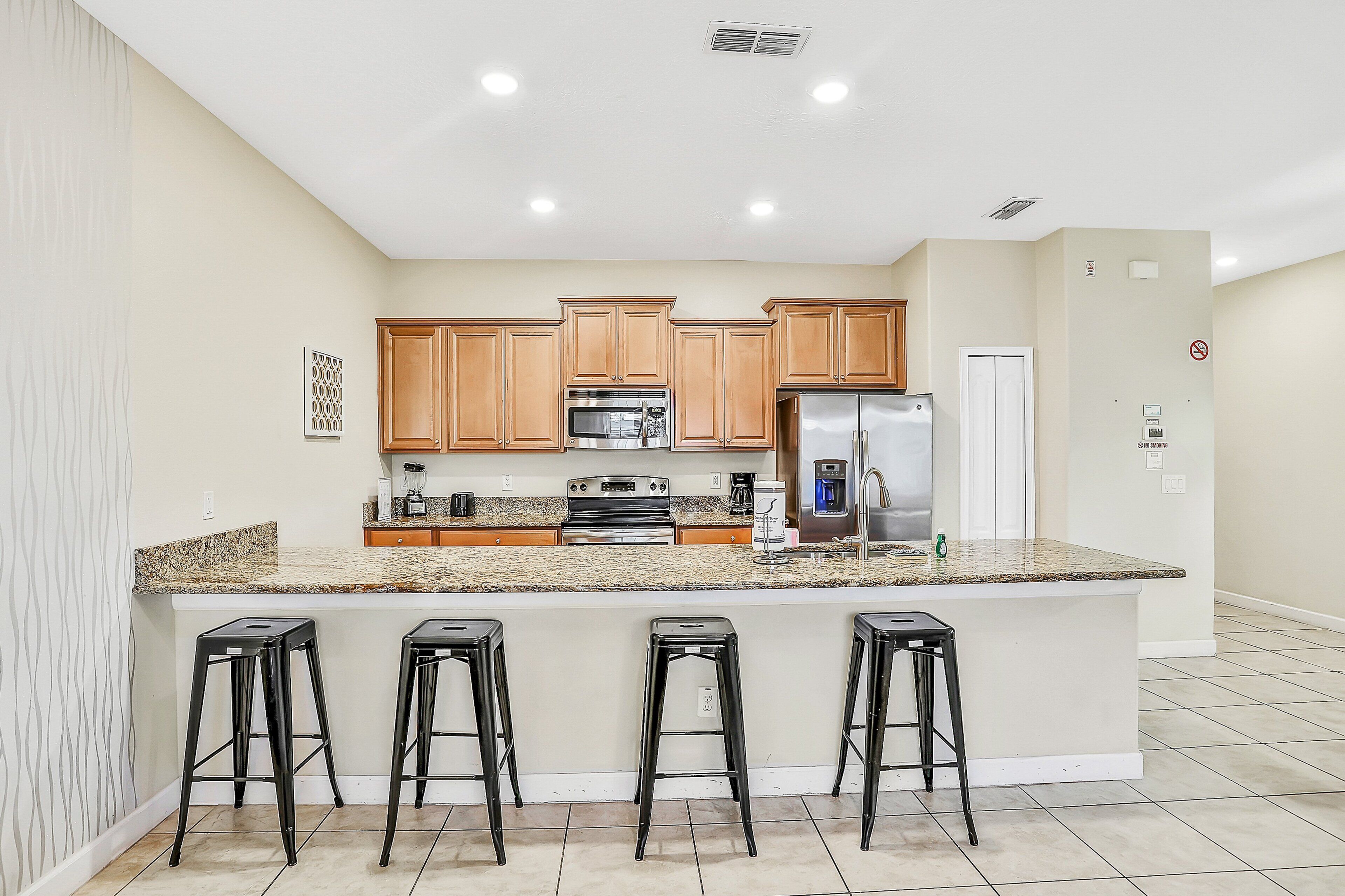 A kitchen with wooden cabinets, a stainless steel refrigerator, a built-in oven, and a granite countertop.