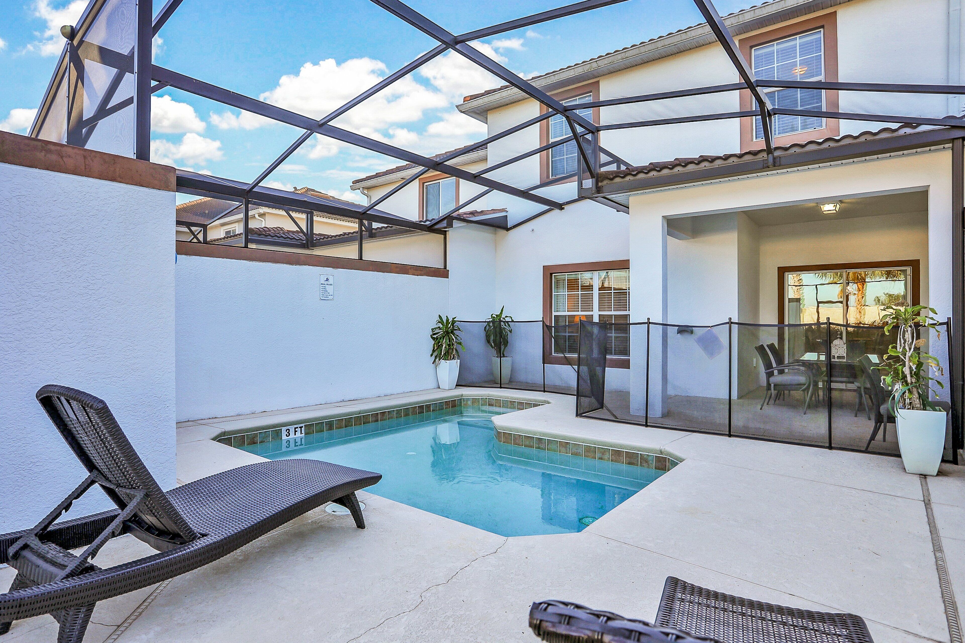 A swimming pool with lounge chairs, a covered patio, and a view of the house.