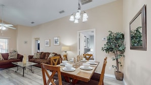 Una sala de estar con comedor, ventilador de techo, candelabro y planta en maceta.