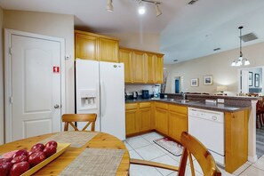 Eine Küche mit Holzausstattung, einem weißen Kühlschrank, einem Esstisch mit Äpfeln und einem Geschirrspüler.