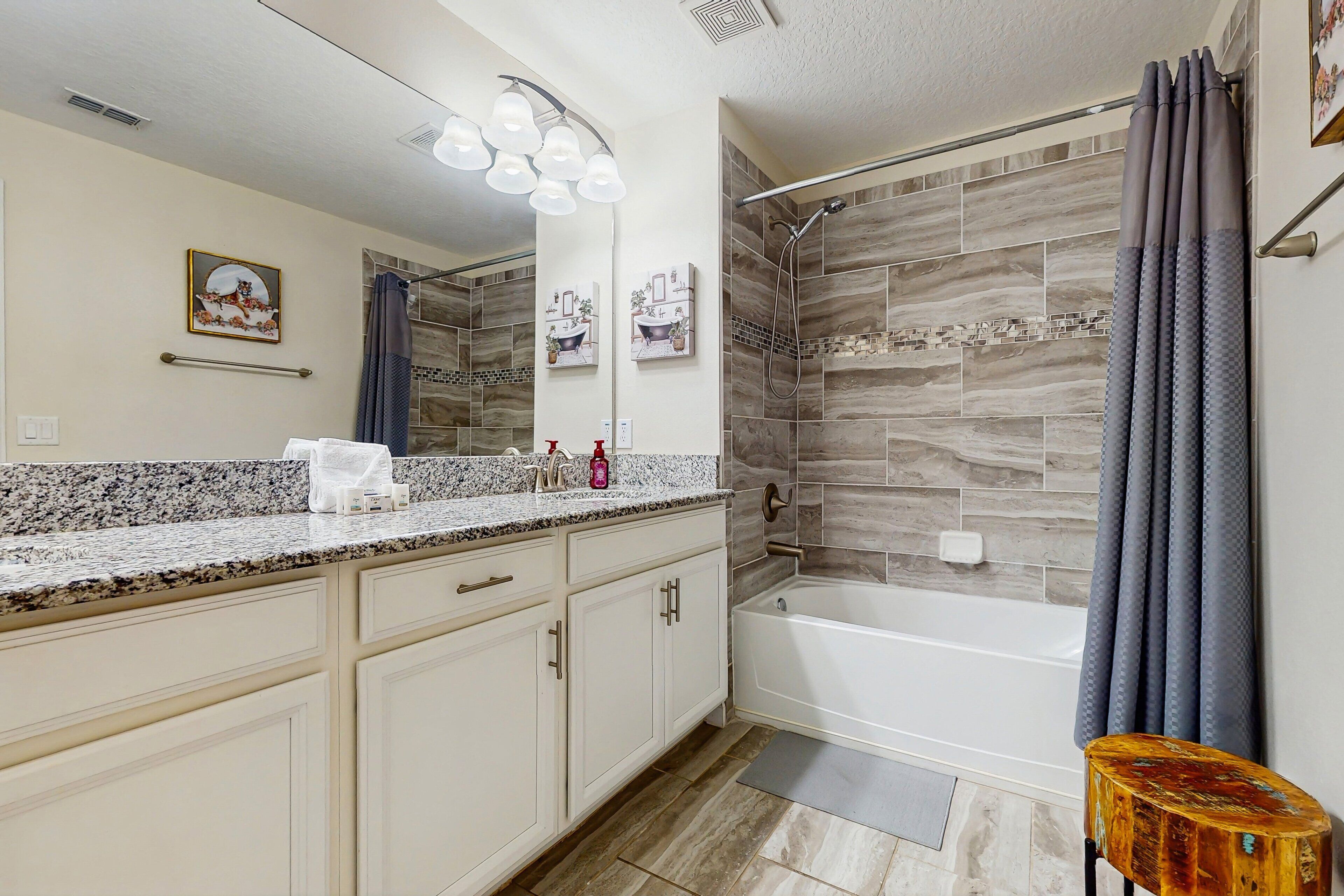 A bathroom with a shower, a vanity with a mirror, and a towel rack.