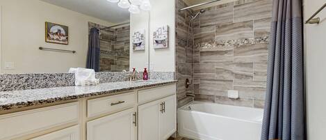 A bathroom with a shower, a vanity with a mirror, and a towel rack.