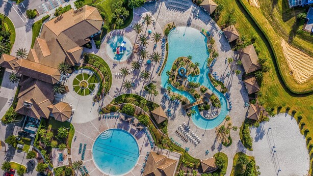 Vista aérea de un resort con varias piscinas, tumbonas y palmeras.