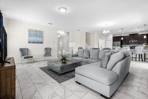 A modern living room with a sectional sofa, a coffee table, and a TV stand. - Luxe Family Retreat With Private Pool, Spa & Resort Amenities (Davenport)