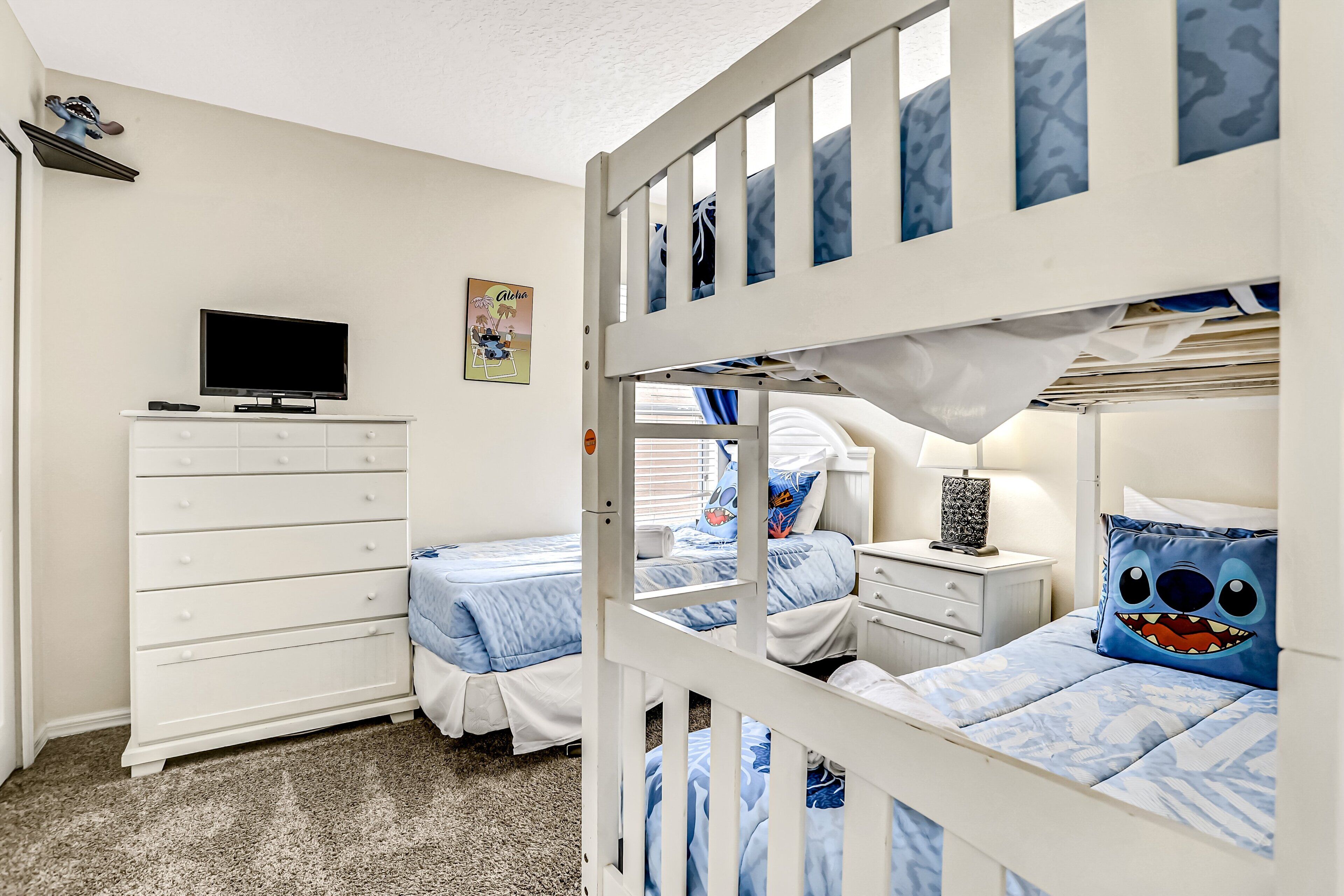 A bunk bed room with a TV, dresser, and artwork on the wall.