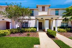 A two-story house with a covered porch, a well-maintained lawn, and a clear blue sky. - Dog-friendly Townhome w/ Private Pool & Resort Water Park - Close to Disney (Davenport)