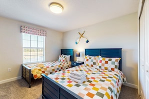 A bedroom with two beds, a window with blinds, a wall-mounted cross, and a nightstand with a lamp. - Dog-friendly Townhome w/ Private Pool & Resort Water Park - Close to Disney (Davenport)