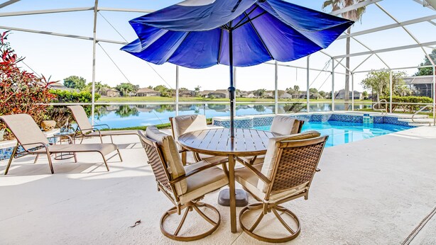 A covered outdoor area with a pool, lounge chairs, and a table with chairs. - Dog-friendly Home w/ Private Pool, High-speed Wifi, and Central AC (Kissimmee)