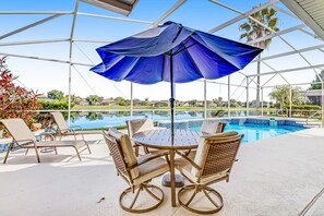 Ein überdachter Außenbereich mit Pool, Liegestühlen und einem Tisch mit Stühlen.