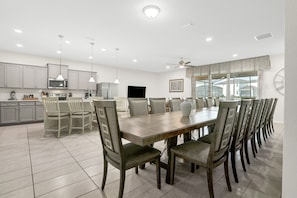 A spacious kitchen with modern appliances, a dining area with a large table and chairs, and a ceiling fan. - Well-stocked Home With Game Room, Enclosed Pool, Patio, & Child-friendly Items (Kissimmee)