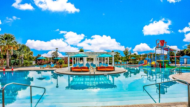 Piscina com espreguiçadeiras e um gazebo.