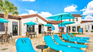 Um hotel com cadeiras de sol ao ar livre, guarda-sóis e um bar com área de lounge.