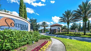 A hotel entrance with a mosaic sign, a pathway, and well-maintained landscaping including hedges and flowers. - Family-friendly Home With Private Pool, spa & Resort Lazy River/water Slide (Davenport)