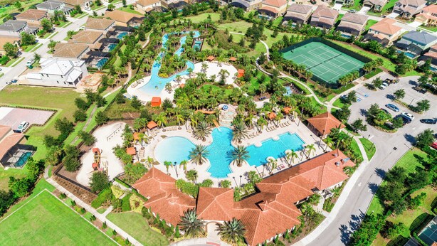 An aerial view of a residential area with a central swimming pool, tennis courts, and a landscaped park. - Family-friendly Home With Private Pool, spa & Resort Lazy River/water Slide (Davenport)