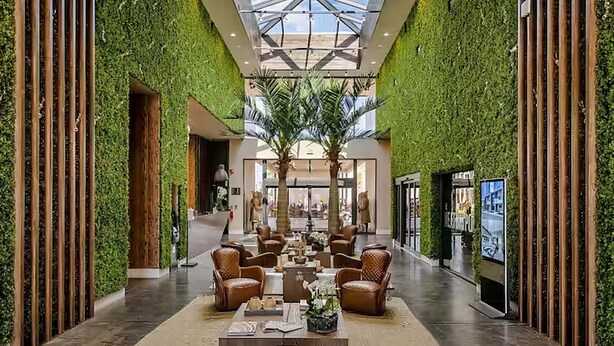 Een hotel lobby met een centrale zithoek, groene wanden en een hoge plafond.
