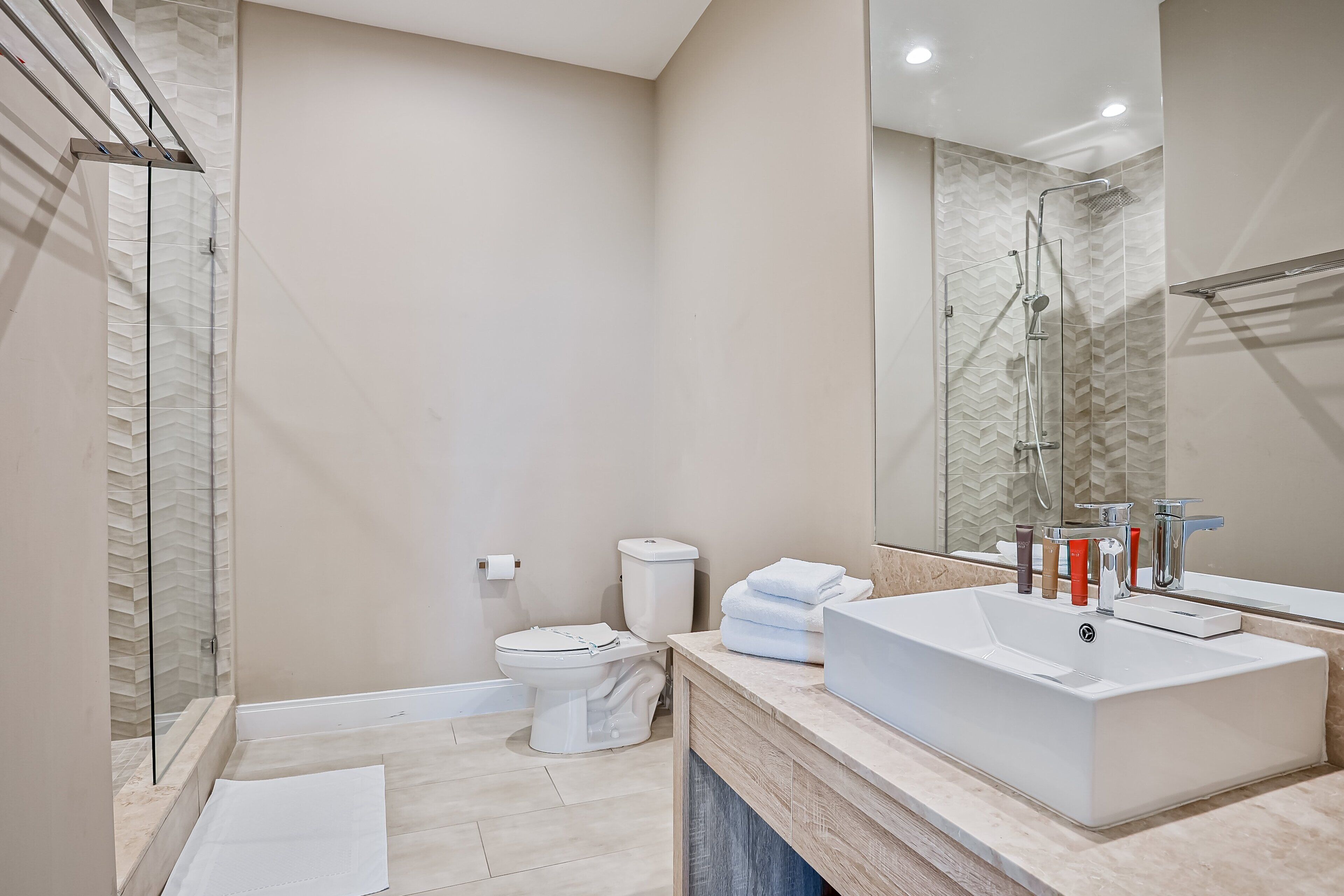 Een moderne badkamer met een inloopdouche, een ruime wastafel en een toilet.