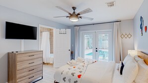 Een slaapkamer met een bed, een televisie, een plafondventilator en uitzicht op de omgeving.