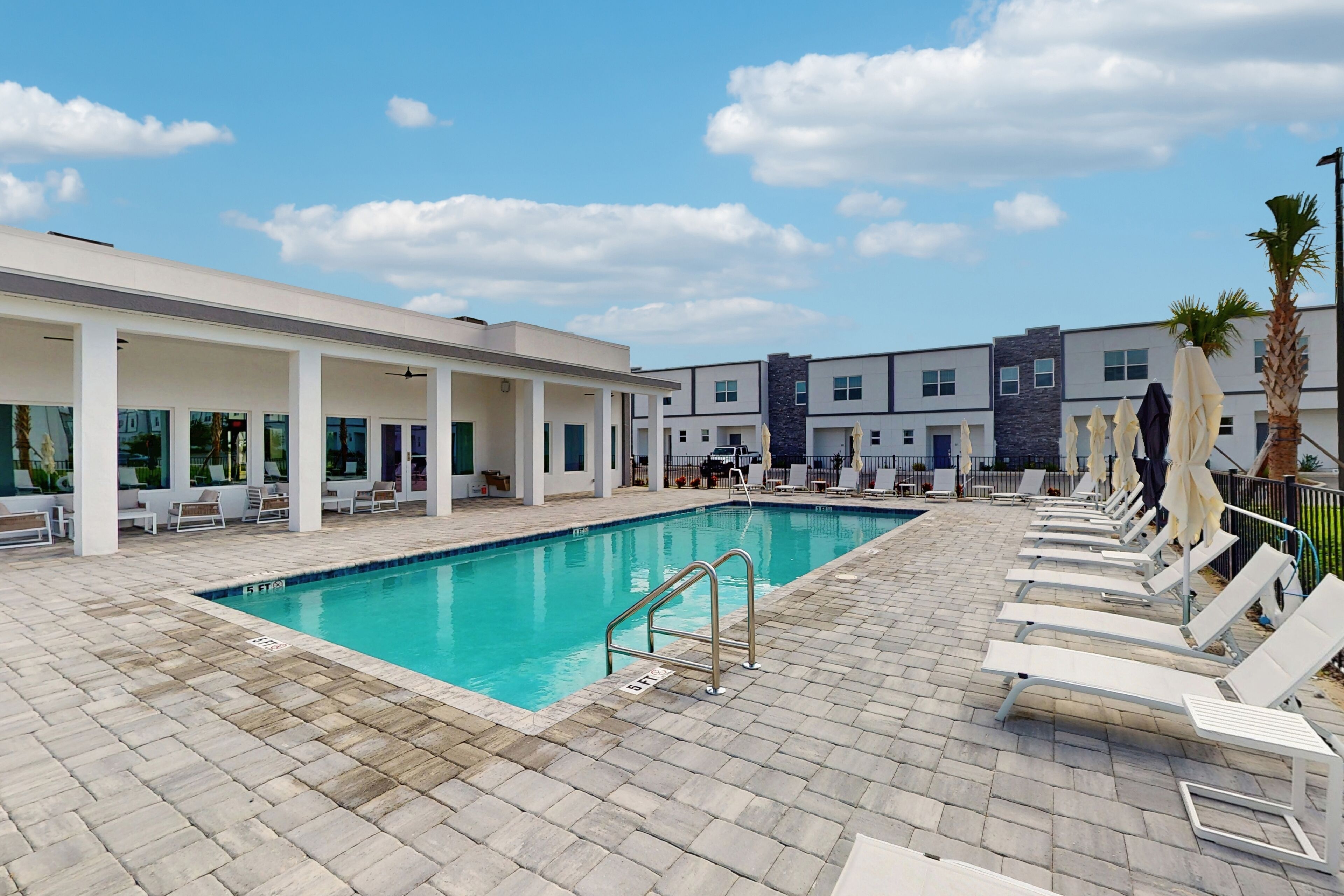 A pool area with lounge chairs and a covered seating area.